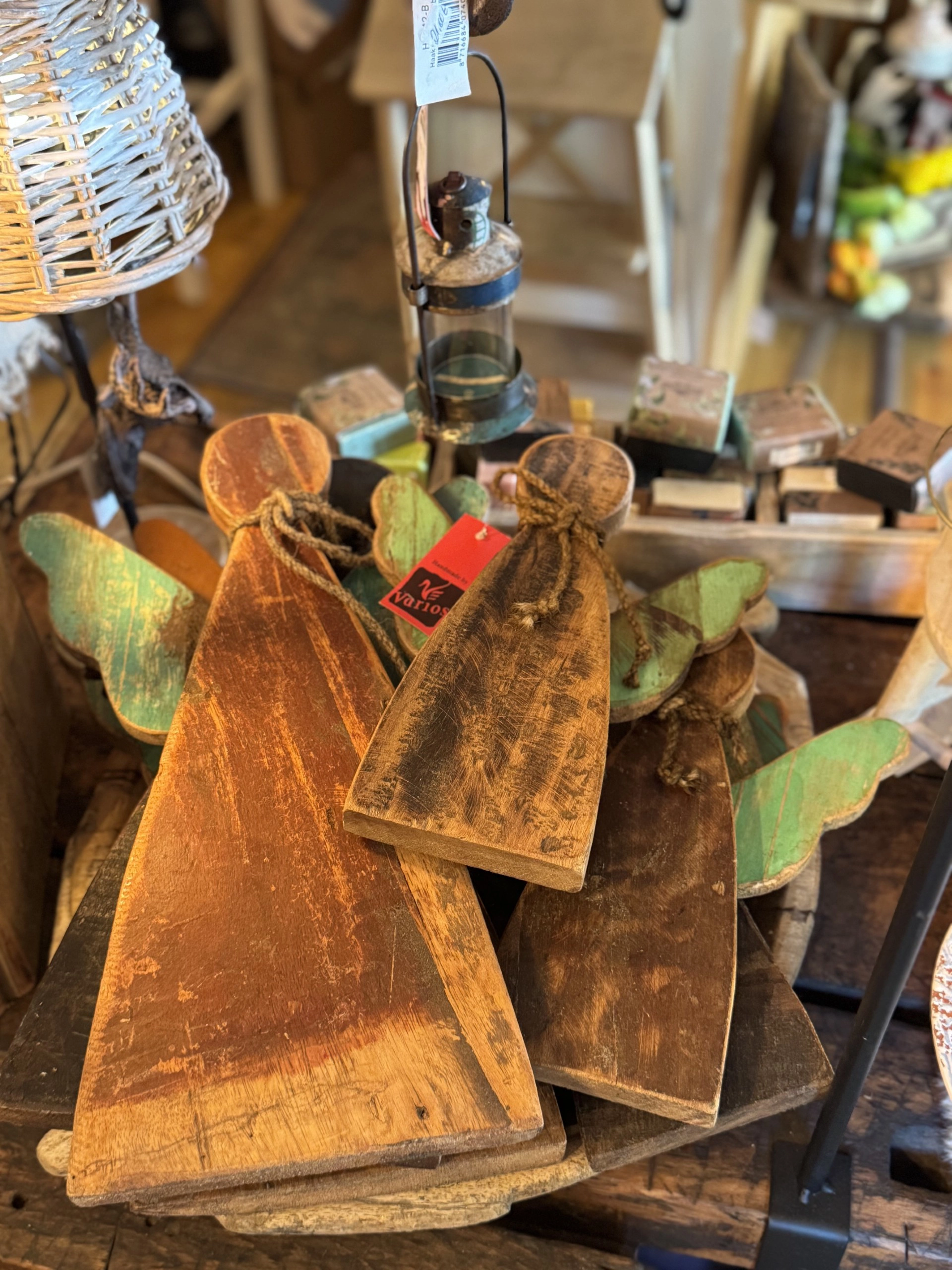 Drei hölzerne Engel mit grünen Flügeln und rotem Anhänger liegen auf einem Holztisch